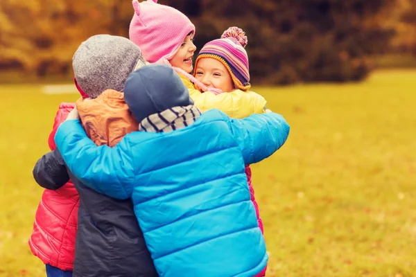 Group of happy children hugging in autumn park — Stock Photo, Image