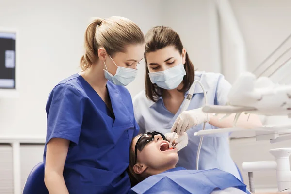 Dentistas mulheres que tratam os dentes da menina paciente — Fotografia de Stock