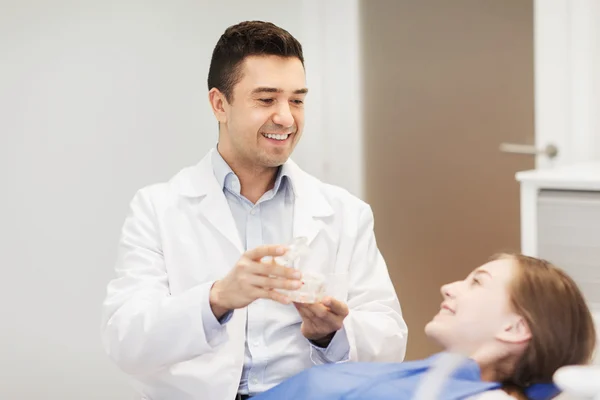 Felice dentista mostrando layout mascella alla ragazza paziente — Foto Stock