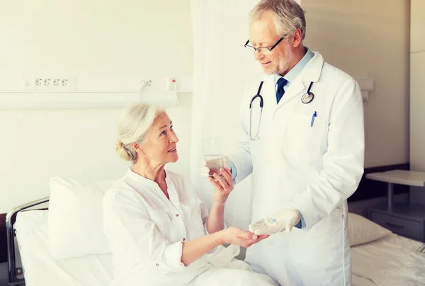 Doctor giving medicine to senior woman at hospital — Stock Photo, Image