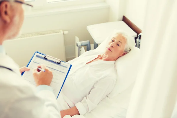 Femme âgée et médecin avec presse-papiers à l'hôpital — Photo