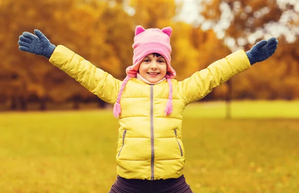 Happy little girl with raised hands outdoors — ストック写真