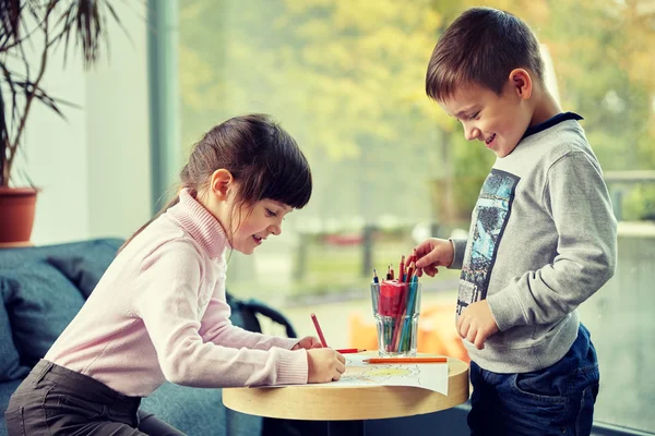 Счастливые девочка и мальчик рисуют дома — стоковое фото