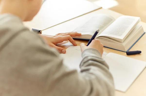 Nahaufnahme eines Schülers, der in der Schule an ein Notizbuch schreibt — Stockfoto