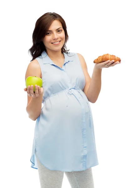 Glad gravid kvinna med äpple och croissant — Stockfoto