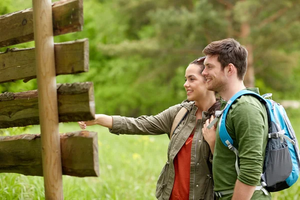 ハイキングのバックパックを道しるべに笑顔のカップル — ストック写真