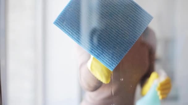 Kvinna i handskar rengöring fönster med trasa och spray — Stockvideo