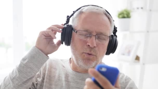 Hombre mayor feliz con teléfono inteligente y auriculares — Vídeos de Stock