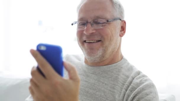 Hombre mayor que tiene videollamada en el teléfono inteligente en casa — Vídeos de Stock