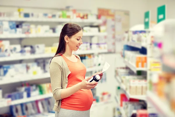 Gelukkig zwangere vrouw met medicatie bij apotheek — Stockfoto