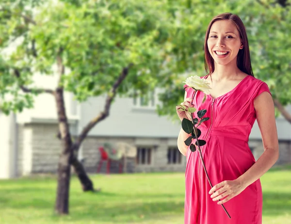 Щаслива вагітна жінка з трояндовою квіткою — стокове фото