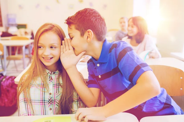 Smiling schoolboy whispering to classmate ear — Stock Photo, Image