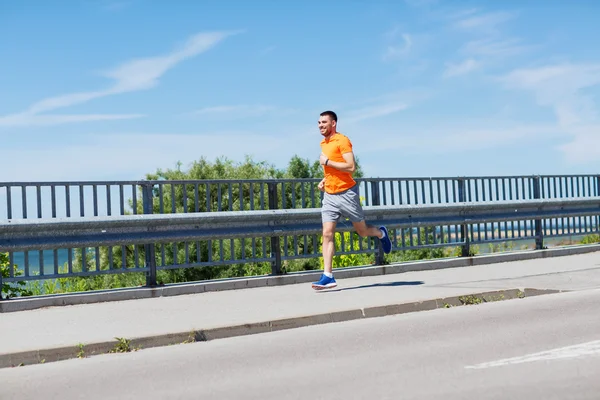 Smiling young man running at summer seaside — Stock Photo, Image