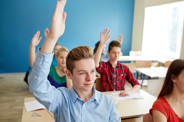 Group of students raising hands at school lesson — Stock Photo, Image