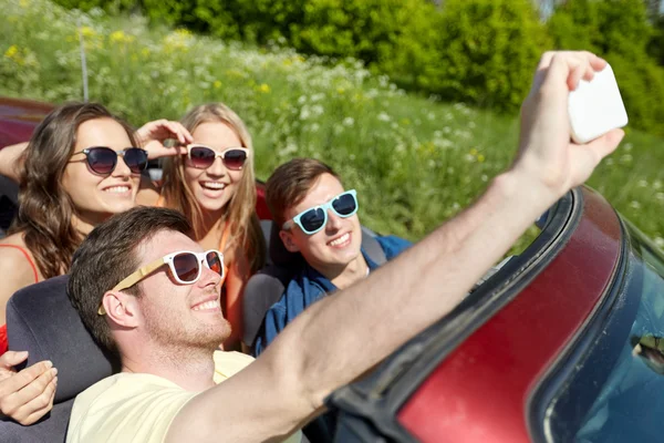 Amigos dirigindo em carro cabriolet e tomar selfie — Fotografia de Stock
