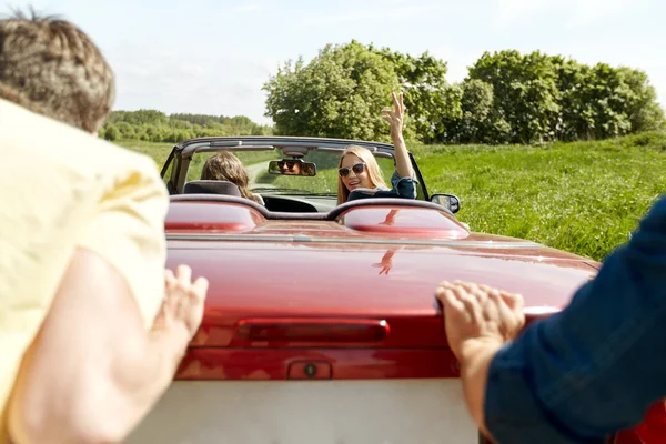 Happy přátelé tlačí auto rozbité kabriolet — Stock fotografie