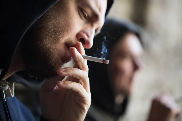 Close up of young man smoking cigarette outdoors — Stock Photo, Image