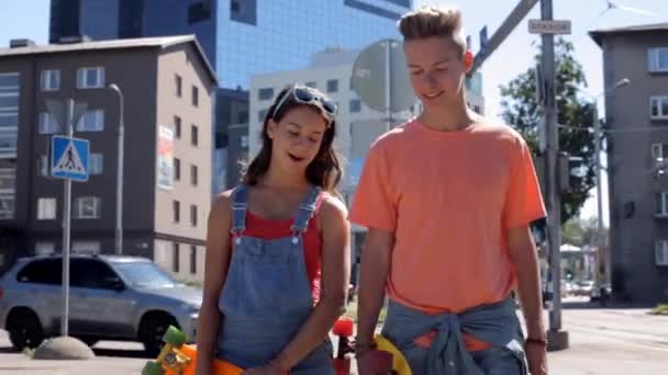 Tiener paar met penny planken lopen in de stad — Stockvideo