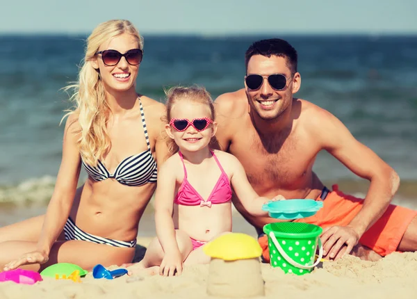 Família feliz brincando com brinquedos de areia na praia — Fotografia de Stock