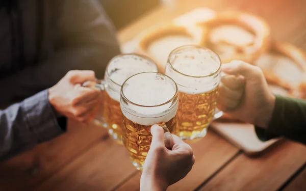 Close up of hands with beer mugs at bar or pub — Stock Photo, Image