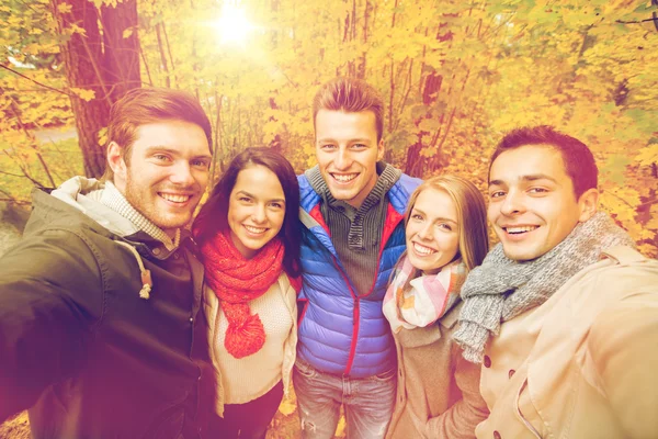 Group of smiling men and women in autumn park — Stock Photo, Image