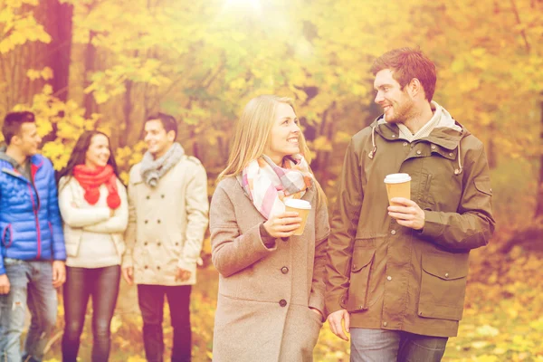 Группа улыбающихся друзей с чашками кофе в парке — стоковое фото