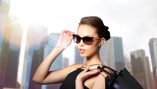 Glückliche Frau mit schwarzer Sonnenbrille und Einkaufstüten — Stockfoto