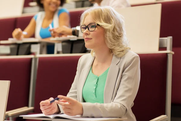 Student girl writing to notebook in lecture hall — Stock Photo, Image