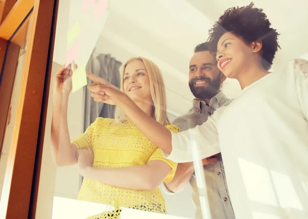 Feliz equipo creativo escribiendo en pegatinas en la oficina — Foto de Stock