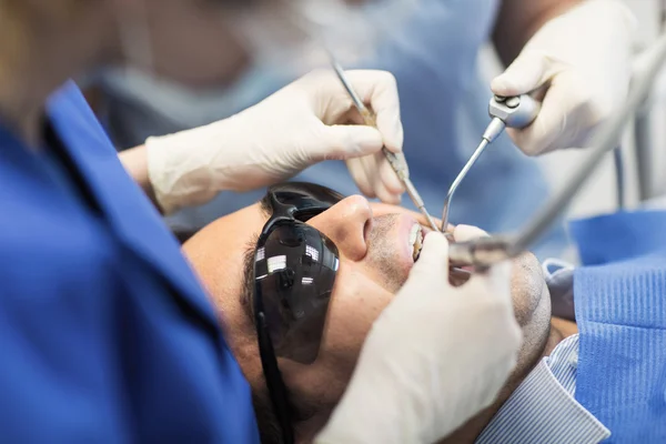 Primer plano de los dentistas que tratan los dientes en la clínica —  Fotos de Stock