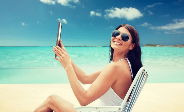 Mulher sorridente com tablet pc banhos de sol na praia — Fotografia de Stock