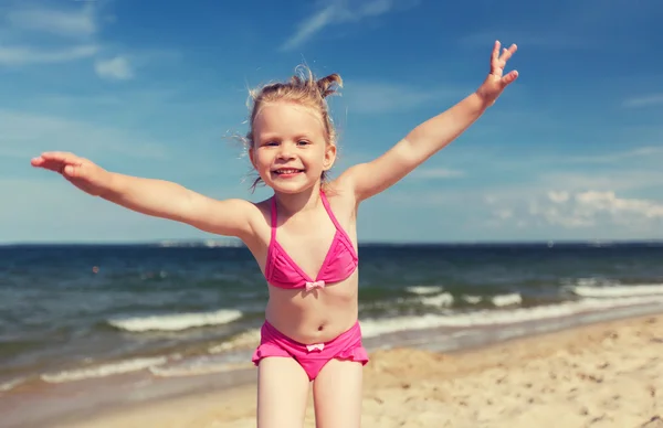 Happy little girl in swimwear having fun on beach — Stock Photo, Image