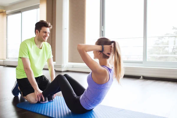 Kvinna med personlig tränare gör sit ups i gym — Stockfoto