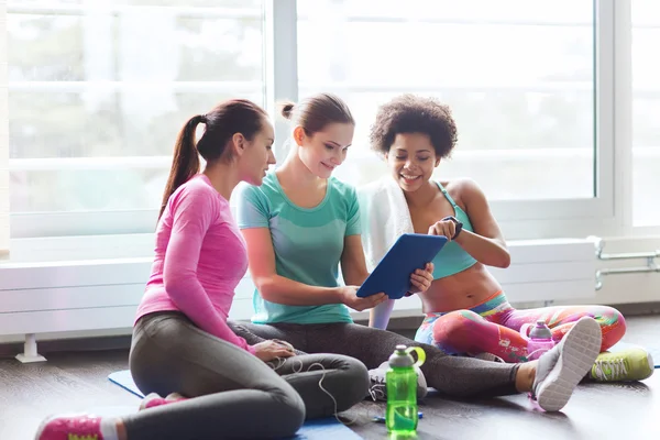 Groep gelukkige vrouwen met tablet pc in sportschool — Stockfoto