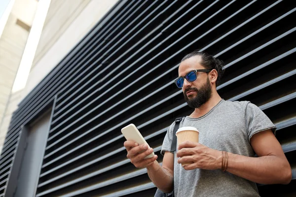 Man with coffee texting on smartphone in city — Stock Photo, Image