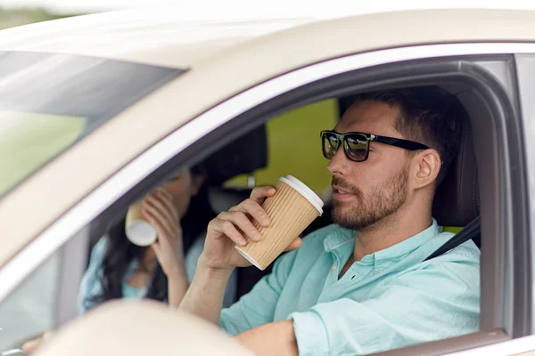 Lycklig man och kvinna i bil med kaffe — Stockfoto