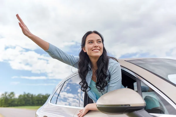 Feliz joven mujer conduciendo en coche y saludando de la mano — Foto de Stock