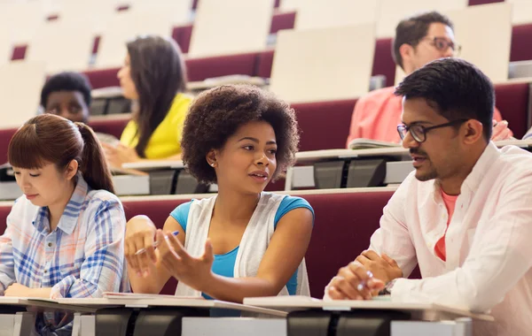 Grupp studenter med anteckningsböcker i föreläsningssalen — Stockfoto