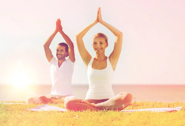 Glimlachend paar oefeningen maken yoga buiten — Stockfoto