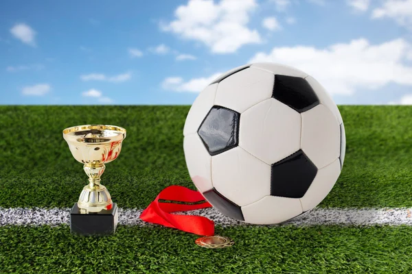 close up of football ball, golden cup and medal