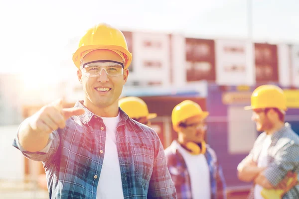 Grupo de construtores sorridentes em hardhats ao ar livre — Fotografia de Stock