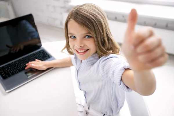 Menina sorridente com laptop mostrando polegares para cima em casa — Fotografia de Stock