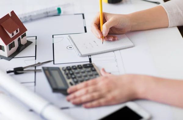 Close up of hand on blueprint writing to notebook — Stock Photo, Image