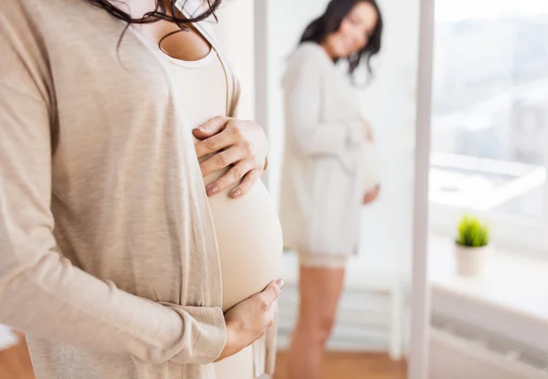 Närbild på gravid kvinna söker till spegel — Stockfoto