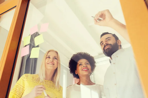 Feliz equipo creativo escribiendo en pegatinas en la oficina — Foto de Stock