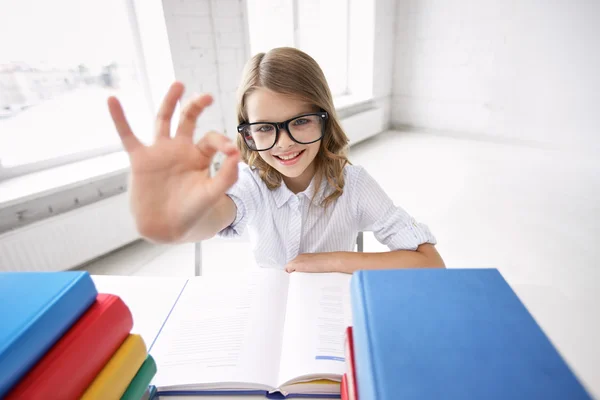 Menina da escola feliz com livros mostrando sinal ok — Fotografia de Stock