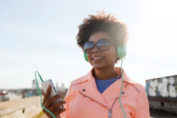 幸福的年轻女人，与智能手机和耳机 — 图库照片