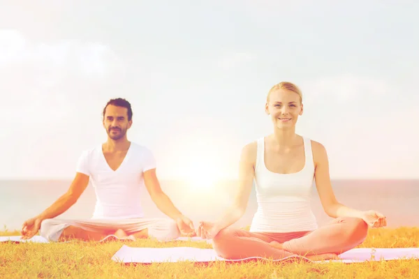 Glimlachend paar oefeningen maken yoga buiten — Stockfoto