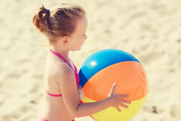 Heureuse petite fille jouant ballon gonflable sur la plage — Photo