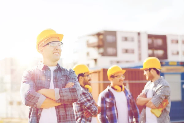 Grupo de construtores sorridentes em hardhats ao ar livre — Fotografia de Stock